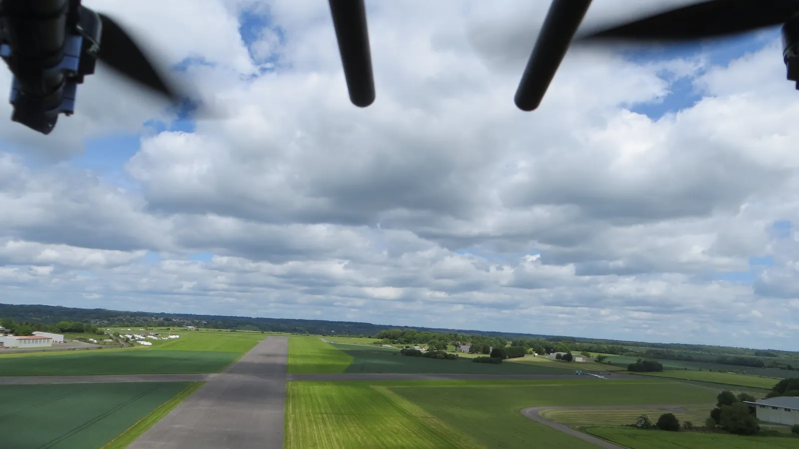 Aerial photograph of a grass airstrip with a light aircraft visible on the runway.