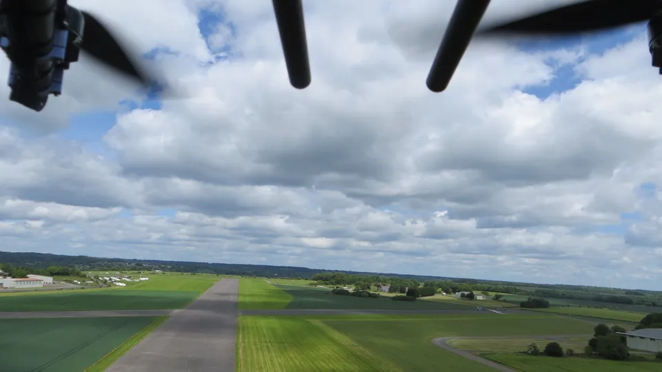 Aerial photograph of a grass airstrip with a light aircraft visible on the runway.