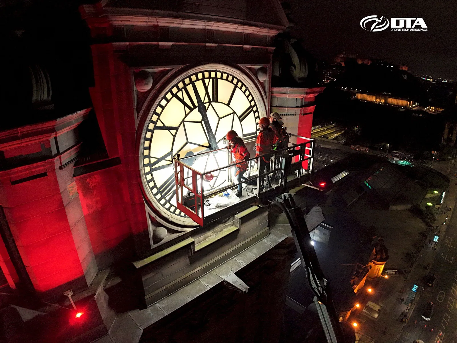Nighttime aerial photograph of a hotel clocktower and rooftop lit against the dark sky.