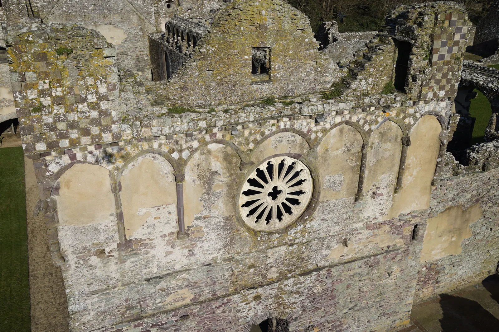 Aerial photograph looking across the roofless nave and surrounding ruined walls of a bishop's palace.