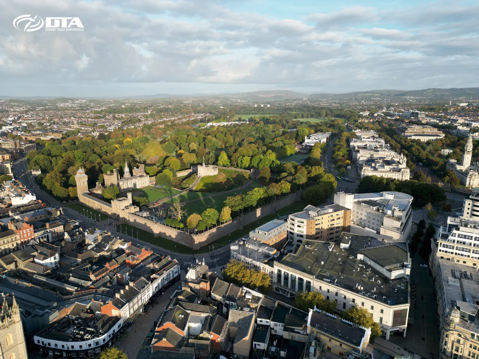 Aerial photograph of a city centre skyline and a castle in soft early morning light.