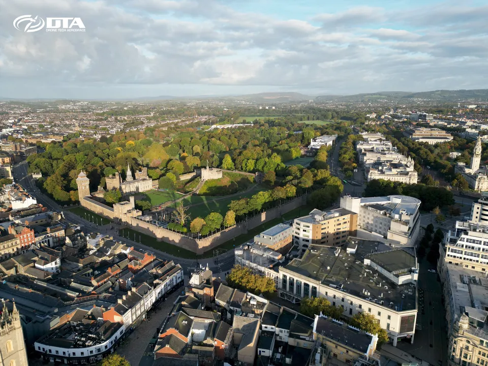 Aerial photograph of a city centre skyline and a castle in soft early morning light.