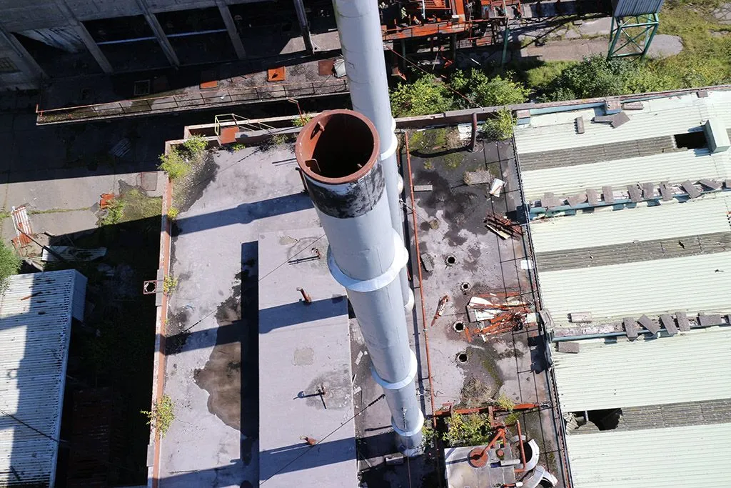 Aerial photograph looking up at a tall industrial chimney or smoke stack during an inspection flight.