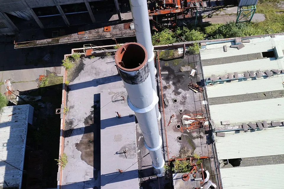 Aerial photograph looking up at a tall industrial chimney or smoke stack during an inspection flight.