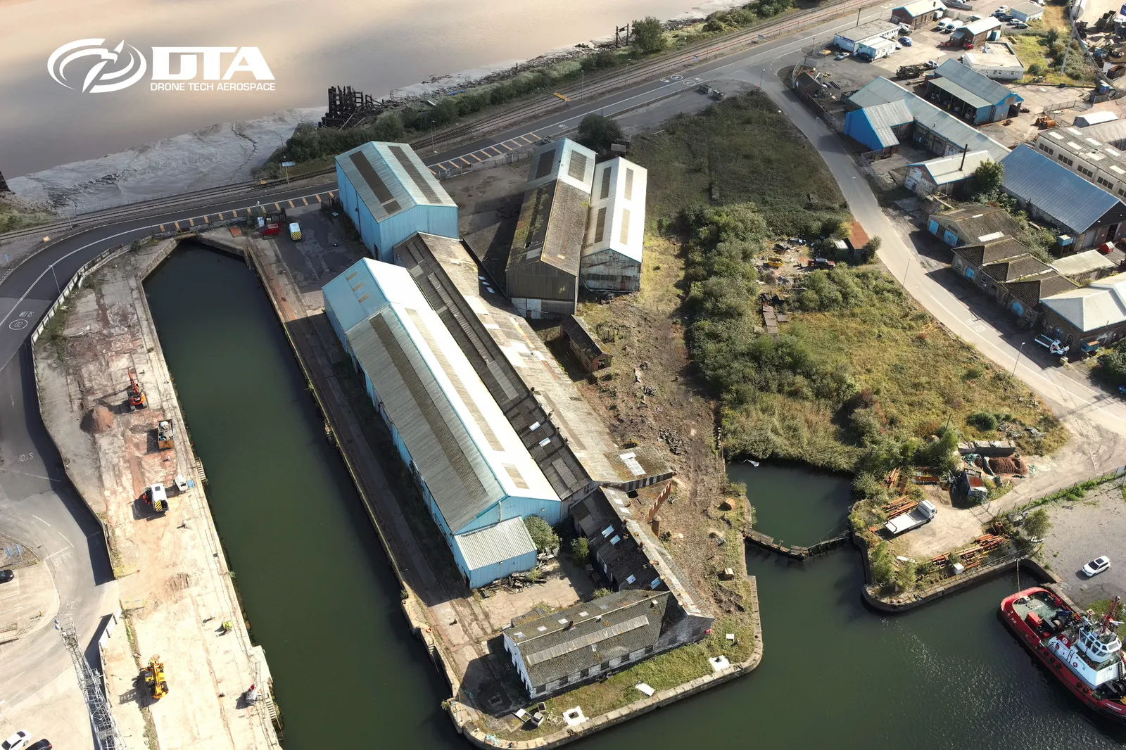 Aerial photograph looking down on a dockside industrial site with berths and storage areas.