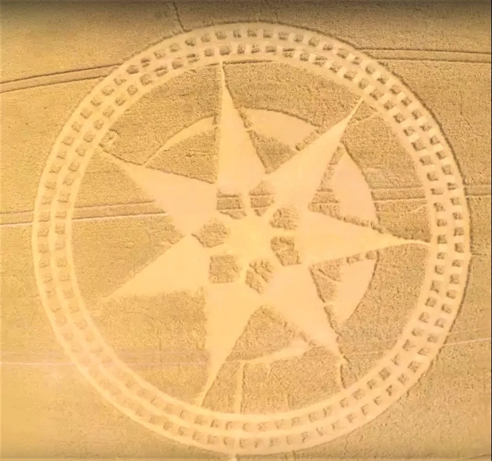Aerial photograph of a large geometric crop circle pattern cut into a field of crops.