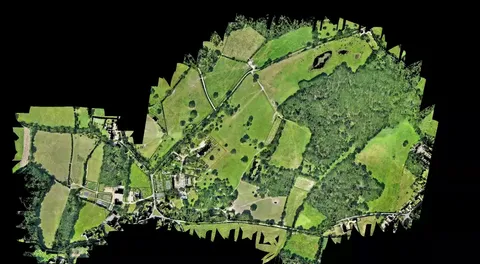 Aerial orthomosaic map of a large rural estate showing fields, woodland, gardens, ponds and buildings against a black background.