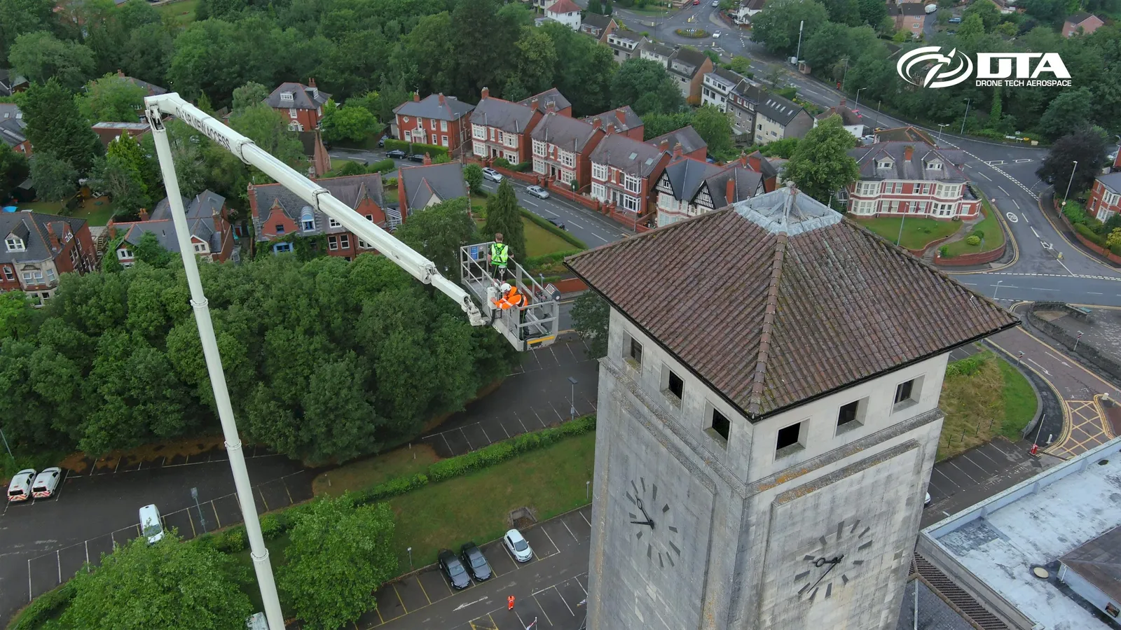 Aerial photograph of a cherry picker platform raised beside a civic building tower.
