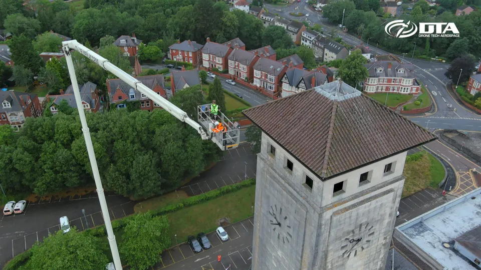 Aerial photograph of a cherry picker platform raised beside a civic building tower.