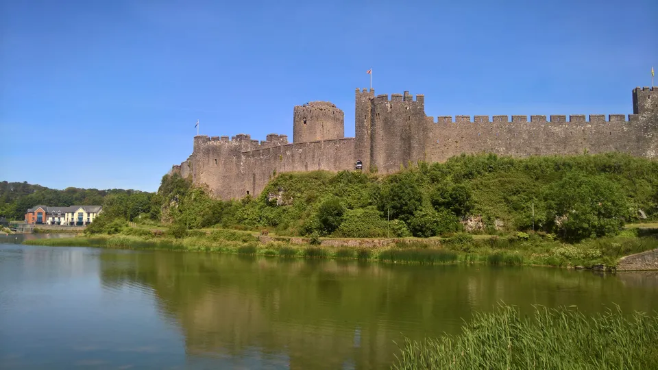 Aerial photograph of a large medieval castle with a round keep beside a tidal river.