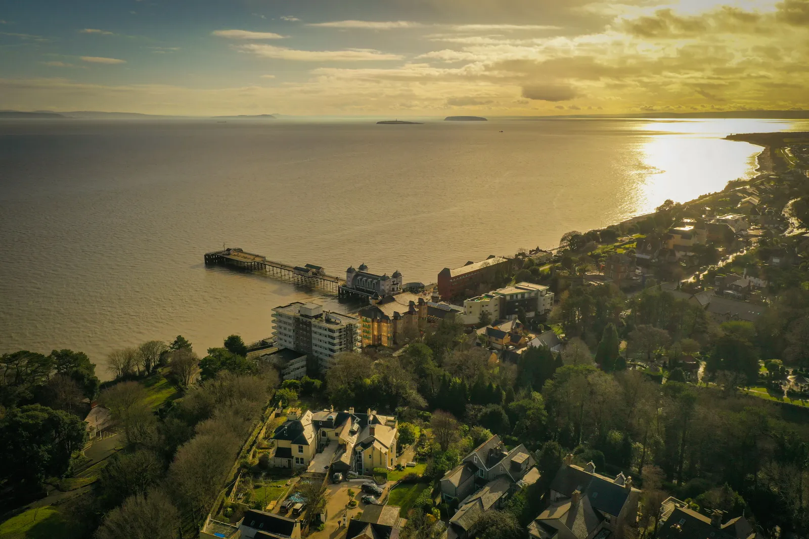Aerial photograph of a Victorian pier stretching into the sea, lit by evening light.