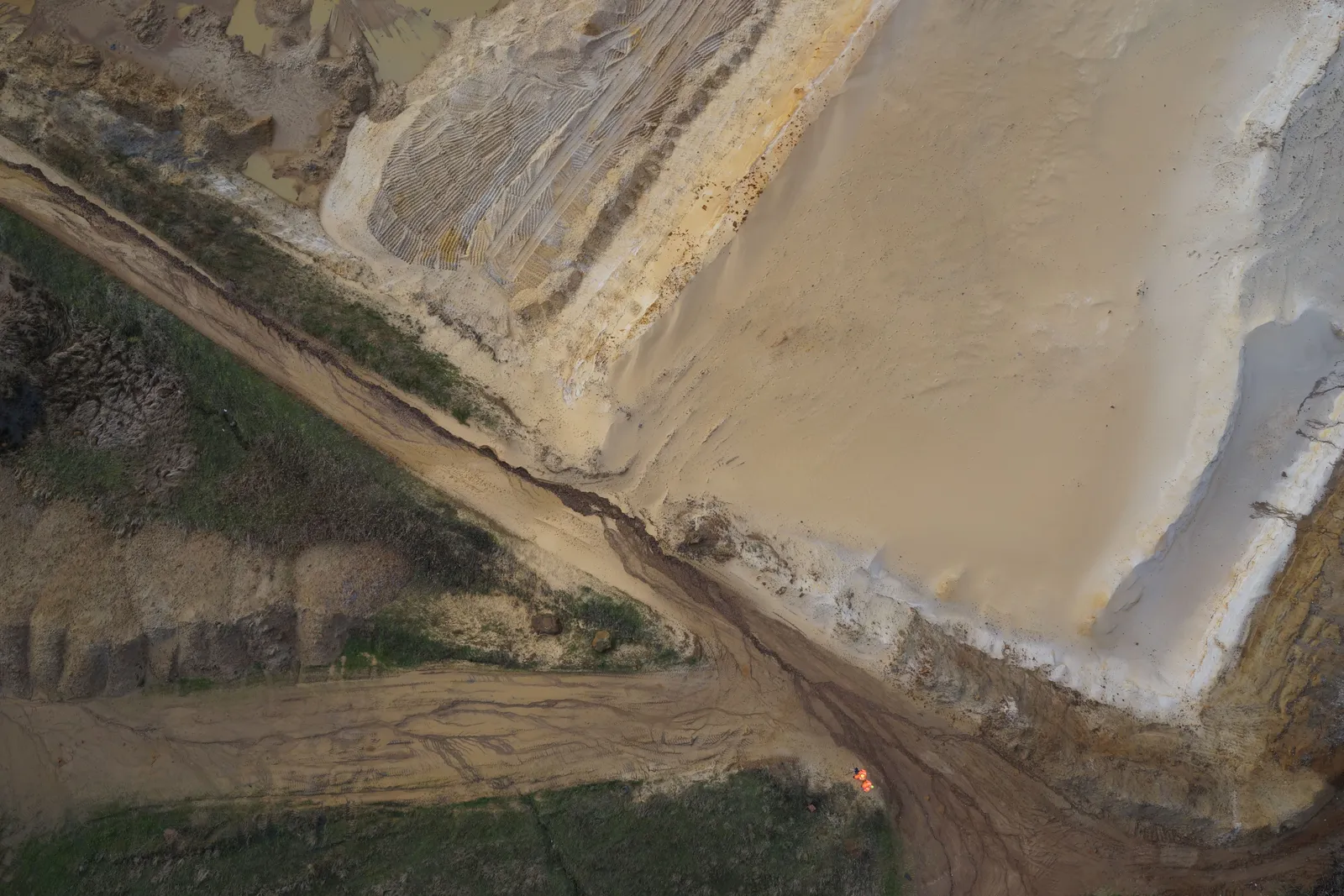 Straight-down nadir aerial photograph of a quarry showing benches, haul roads and stockpiles.