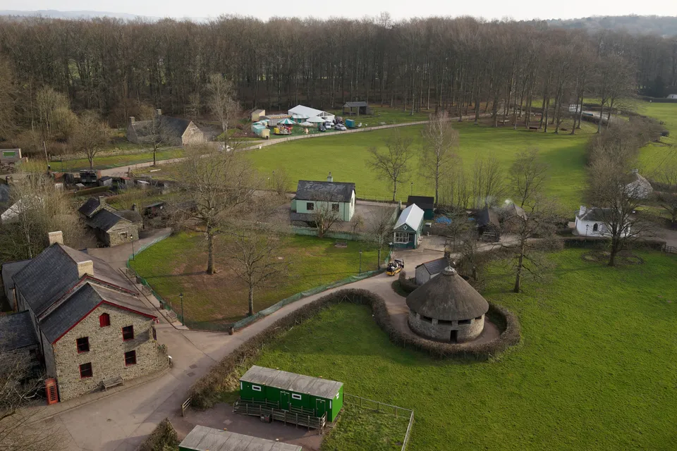 Aerial photograph of parkland, pathways and reconstructed buildings at St Fagans National Museum of History.