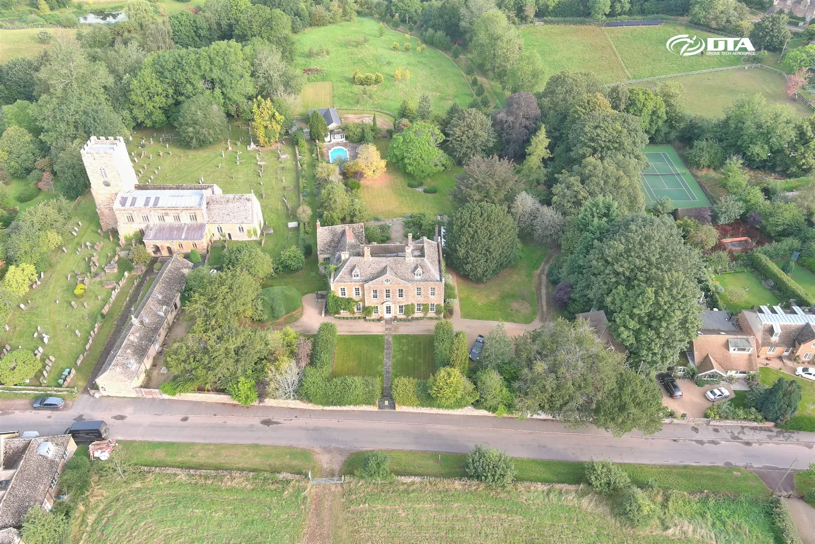 Aerial photograph of a country house and driveway set within landscaped grounds.