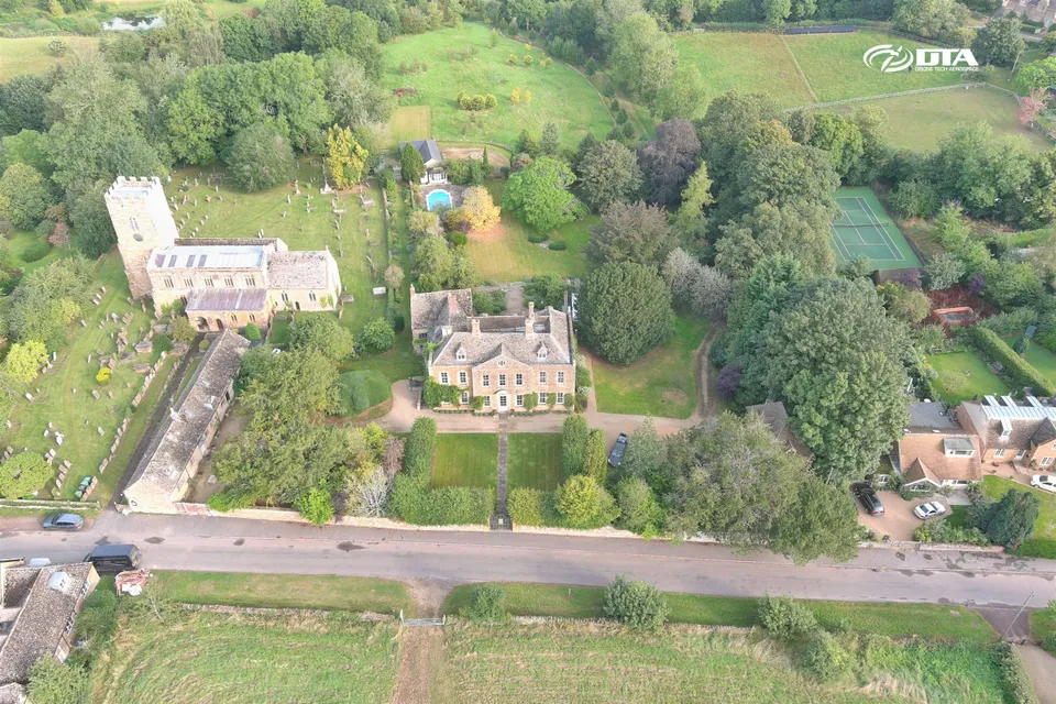 Aerial photograph of a country house and driveway set within landscaped grounds.