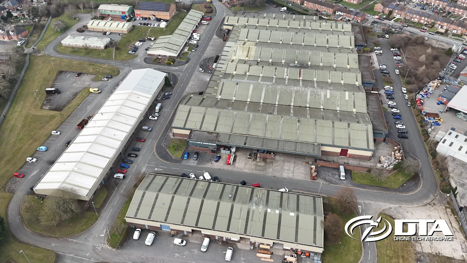 Aerial photograph looking down on a row of industrial estate units and yards.