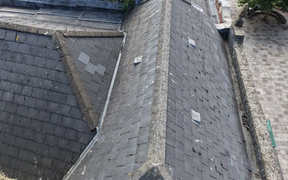 Close-up drone image of slate roof coverings showing slipped and patched slates, Cardiff