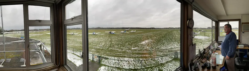 Panoramic view from inside Denham ATC tower overlooking the airfield with parked light aircraft