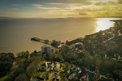 Aerial drone photo of Penarth Pier and pavilion at sunset with the Bristol Channel and Somerset coast in the distance